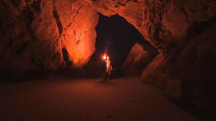 Man entering the cave of his fears with a torch